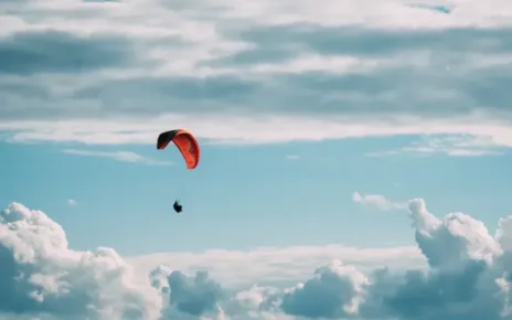 person in red parachute under white clouds during daytime